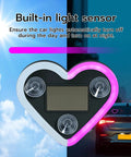 Heart Shaped Car LED Ambient Light With Solar Rechargeable Power showing pink glow and built-in light sensor with car background