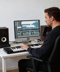 A man using High Density Acoustic Isolation Pads 2 Pack Studio Monitor Speaker Foam under speakers on a desktop.