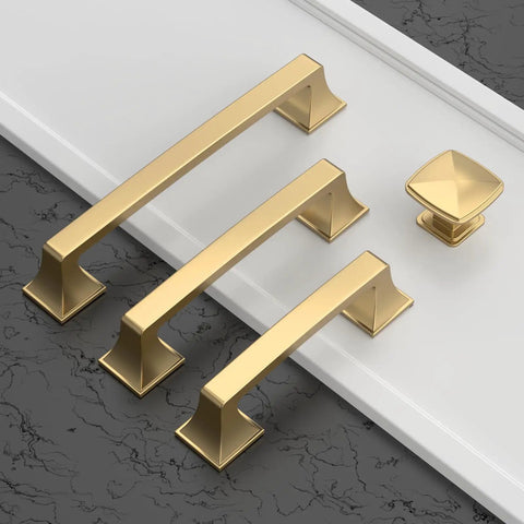 Gold cabinet handles and knob displayed on a textured surface
