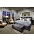 Elegant modern bedroom with plush gray bed, beige chairs, side tables, and patterned curtains overlooking a large window.