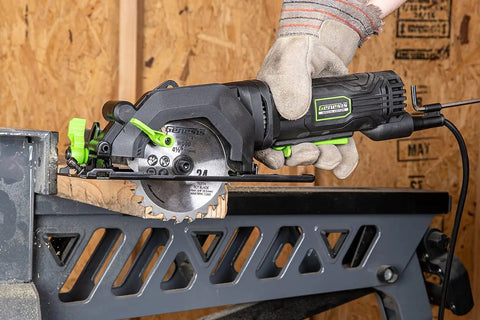 Genesis Mini Circular Saw 4.0 Amp 4-1/2 Inch With 24-Tooth Carbide Blade in use on wood beam, shown with hand grip and bevel cut action.