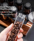 Keep Your Grounds Fresh As A Bell With This Six Tube Single Dose Coffee Bean Storage Jar Set Featuring One Way Exhaust Valves And A Smart Hopper For Flawless 22 To 25 Gram Portions To Brew On Point Daily, showing a glass tube filled with coffee beans.