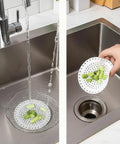 Universal Five Inch Silicone Shower Drain Hair Catcher in action, catching food debris in a kitchen sink.