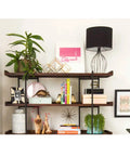 Built Different Heavy Duty Black Iron Bookshelf With Real Wood Shelves used for displaying plants, decor, and books in a stylish setup.