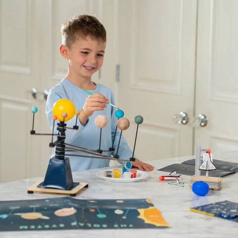 Totally Build It Yourself Space Explorer Kit For Kids Ages Five Plus With Real World Science Lessons Spin A Mini Solar System Build And Launch Model Rockets Paint Space Crafts And Learn How Astronauts Fly. Boy painting solar system model with kid space science kit