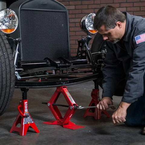 Mechanic using Heavy Duty Steel Scissor Lift Jack 1.5 Ton Car Kit under vintage car for lifting during maintenance
