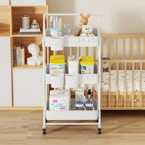 Three-Tier Folding Rolling Utility Cart With Wheels Foldable Storage Organizer With Three Hanging Cups And Six Hooks For Kitchen Office Living Room Nursery White Ideal For Home Organization And On The Go Use, placed in a nursery setting with toys and baby supplies.