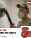 Person using Pro Grade 70 Pack 9 Inch Sanding Discs Hook And Loop Self Stick 8 Hole for drywall sanding, includes assorted grits.