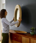 Person hanging a mirror using Claw Drywall Picture Hanger Set, Holds 45 Lbs Per Hook, Includes 3 Hooks And 3 Spot Markers, Stainless Steel Silver Finish, No Studs Needed, Heavy Duty Wall Hanging For Pictures And Mirrors on a black wall above a wooden console.