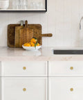 10 Pack Brushed Brass Kitchen Cabinet Knobs with Knurled Texture installed on white drawers in a modern kitchen setting.