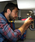 Person using Hands Free 200 Lumen LED Neck Light for Work and Outdoors With 4 Modes Water Resistant Rugged Workhorse Design fixing pipes