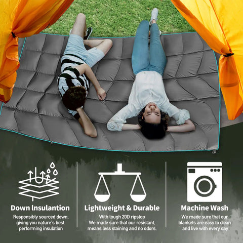 Two people relaxing on an Outdoor Puffy Camping Blanket With Lightweight Down Alternative Fill, under a tent in a grassy area.