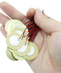 Hand holding Twenty Piezo Discs Transducers 27mm With 3.94 Inch Leads And 100mm Cables for DIY projects, brass ceramic elements