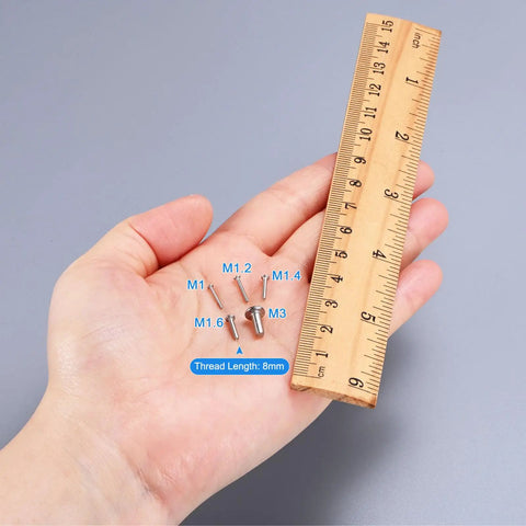No Fuss Flat Head Machine Screws M1.4X14MM 304 Stainless Steel Phillips Drive beside ruler for size reference.