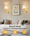 Gold Cordless Wall Sconces Set Of Two Battery Operated Rechargeable Dimmable Led Lamps With Fabric Shades on a living room wall.