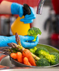 Person wearing Heavy Duty Nitrile Disposable Gloves 4 Mil Thick, 100 Count, Latex Free And Powder Free while washing vegetables.