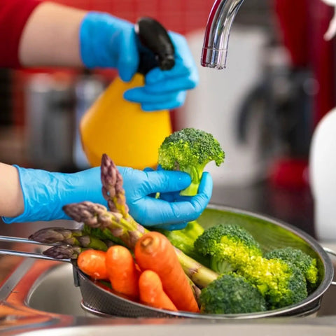 Person wearing Heavy Duty Nitrile Disposable Gloves 4 Mil Thick, 100 Count, Latex Free And Powder Free while washing vegetables.