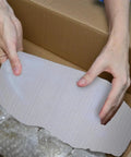 Hands holding a 100 Pack White Foam Cushioning Pouches For Lightweight Shipping And Moving, Provides Superior Shock Protection.