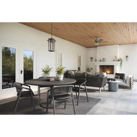 Boxwood Collection 1-Light Outdoor Wall Lantern With Clear Seeded Glass lighting a modern patio area with wicker furniture.
