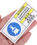 Factory Grade Industrial Equipment Maintenance Warning Sticker With PET Material held in hand, showing caution and cleaning symbols.