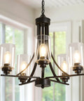Five Light Black Glass Chandelier With Rustic Metal Pendant Lighting hung in indoor setting with windows in background.