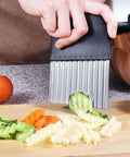 Crinkle cutter with stainless steel comb blade and black handle for kitchen use, slicing cucumbers and carrots.