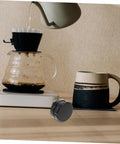 Pro Grade Reusable Metal Tamper Set For Espresso Machines next to dripper and cup on counter