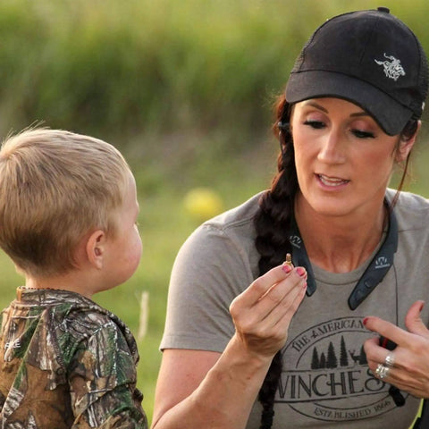Woman explaining hunting technique to child, wearing a Behind The Neck Bluetooth Hearing Enhancer For Hunters With Retractable Earbuds.