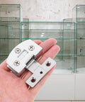 Heavy Duty Stainless Steel Glass Door Hinges With No Sweat Drill Free Mount For Tempered Glass Panels shown in hand by display cabinet.