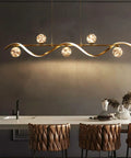 Modern Linear Pendant Light Set Featuring Six Glass Globe Shades Dimmable Gold Kitchen Island Fixture above a dining table.