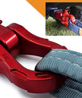 Close-up of red aluminum bow shackle connecting tow strap, Aluminum Alloy Ultra Bow Shackles For Off Road Recovery, attached to vehicle.