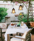 Three Pack Battery Operated Outdoor Chandelier Pendant Lights With Rustic Black Metal Bell Shade for gazebo patio porch decor above a table.