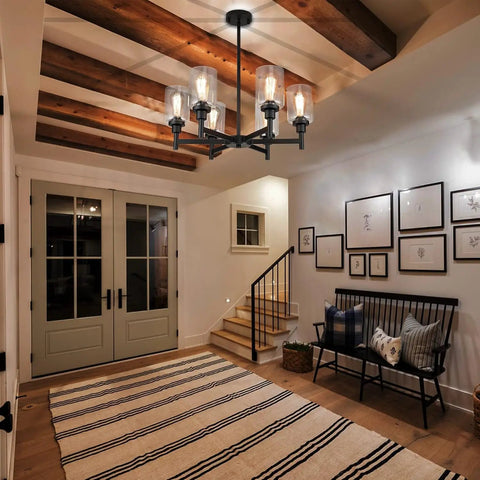 Black Farmhouse Chandelier With Six Clear Glass Shades Hanging Over Dining Table Featuring Sturdy Metal Frame And Sleek Modern Design That Hits Different For A Killer Centerpiece Vibe In Any Home Space in an entryway with a rug.
