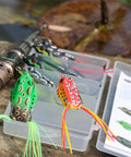 Five Piece Topwater Frog Lures Set For Freshwater Fishing Catch Bass And More Ray Frog Soft Baits in tackle box on rock