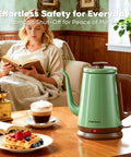 Gooseneck Electric Kettle 1L For Precise Pour Over Coffee And Tea Stainless Steel BPA Free Green Finish Ergonomic Handle Fast Heating Classic Pour Over Kettle For Home Barista on a table with breakfast beside a seated person reading