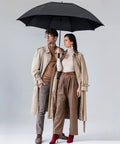 Oversized 54 Inch Windproof Golf Umbrella With Double Canopy held by two people in coats, showcasing rain protection, Black