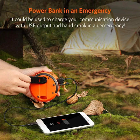 Person using USB Rechargeable Camping Lantern With Hand Crank to charge phone, tent in background, outdoor setting