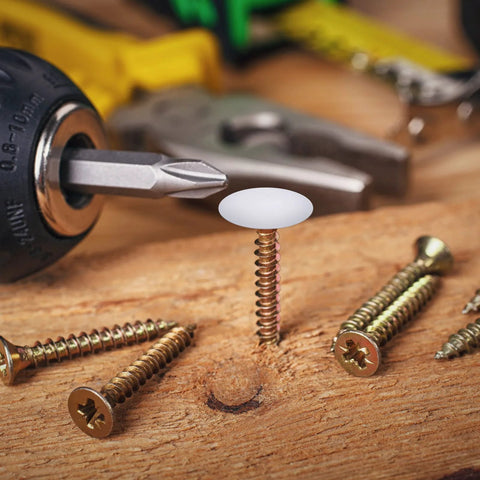 Plastic Self Tapping and Self Adhesive Screw Hole Covers for Wood Furniture, white cap on screw in wooden surface with tools nearby.
