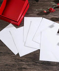 Bulk White B6 Card Envelopes 50 Pack Self Sealing 15.7 X 10.6 Cm displayed next to a red box on a wooden surface