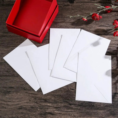 Bulk White B6 Card Envelopes 50 Pack Self Sealing 15.7 X 10.6 Cm displayed next to a red box on a wooden surface