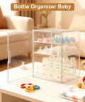 Three Tier Baby Bottle Organizer With Removable Dividers For Bottles Nipples Pump Parts And Food Jars Clear Acrylic Bottle Station For Countertop And Kitchen Perfect Gift For Busy New Moms shown on a table with baby toys and a couch in background