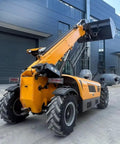 Powerful Industrial Telehandler Forklift Featuring Auto Leveling Boom And All Terrain Capability with elevated bucket and rugged tires.