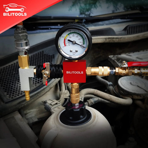 Front view of red BILITOOLS coolant pressure tester attached to a car radiator with brass fittings and gauge.