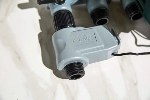 Close-up of water connector with hoses for Automatic Yard Watering System With Four Station Sprinkler Setup Large Digital Display Easy Dial Controls And Three Start Times For Smart Effortless Lawn And Garden Hydration