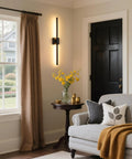 Cordless Black Rechargeable Wall Sconce With Remote 8000Mah Battery Operated mounted on wall beside beige curtains and cozy couch.