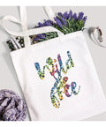 White tote bag with 'Wild & Free' in colorful tiger print vinyl from Glitter Animal Pattern Heat Transfer Vinyl Tiger Print 12x12 Inch Sheet For T Shirts And Fabrics Iron On Dope DIY Craft Supplies With Bold Colors And Rough Glitter Texture For Custom Tees.