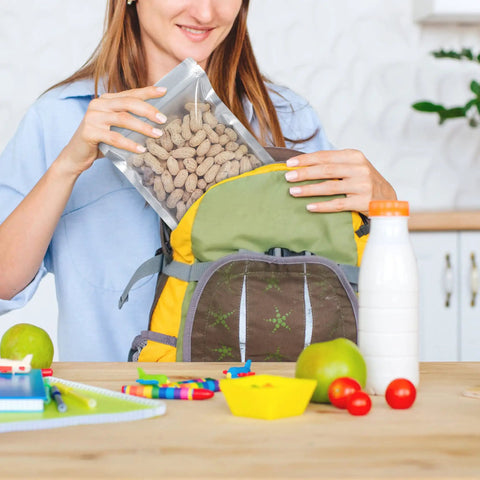 Person placing 50 Pack Mylar Bags For Food Storage With Clear Window In 1 Quart Size into backpack