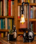 Black Industrial Skull Lamp With Skeleton Decor For Gothic Bedroom Dope Handcrafted Cast Iron And Resin Skull Table Lamp Vintage Industrial Vibe UL Certified 18.5 Inches Tall 1 to 40W Bulb Not Included on wooden table