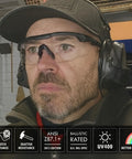 Man wearing Anti Fog Tactical Shooting Glasses For Men Built Tough Military Grade Ballistic Eye Protection For Range Swat Medical And Dental Use ANSI Z87.1 Plus OSHA Compliant MIL PRF 32432A Tested Durable Frame, indoors with headphones