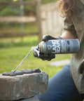Person applying Slick Landscape Foam Adhesive Quick Cure Gap Sealant That Locks Tight On Stone And Concrete for repair on patio stones.